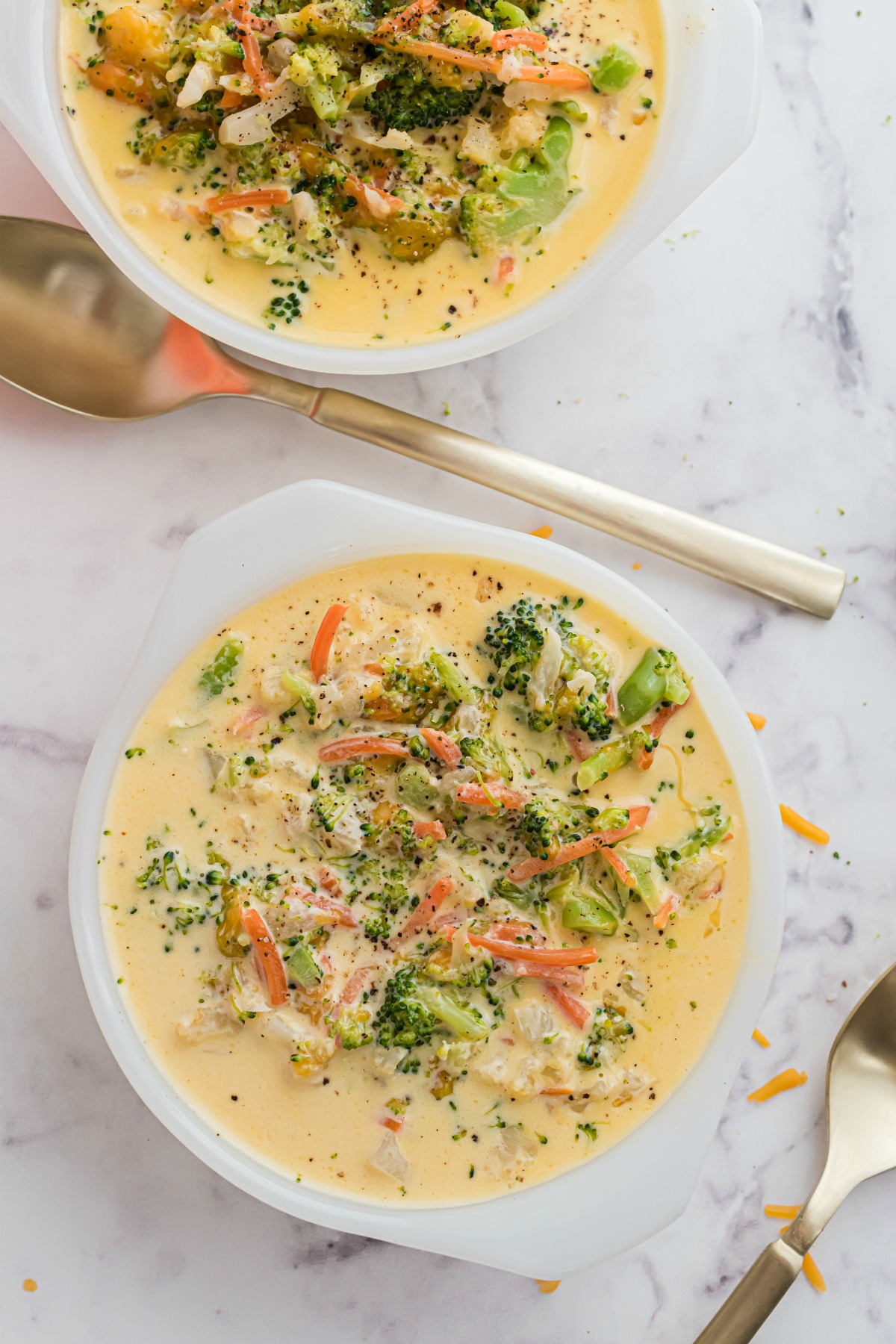 Broccoli cheese soup served in two white bowls.