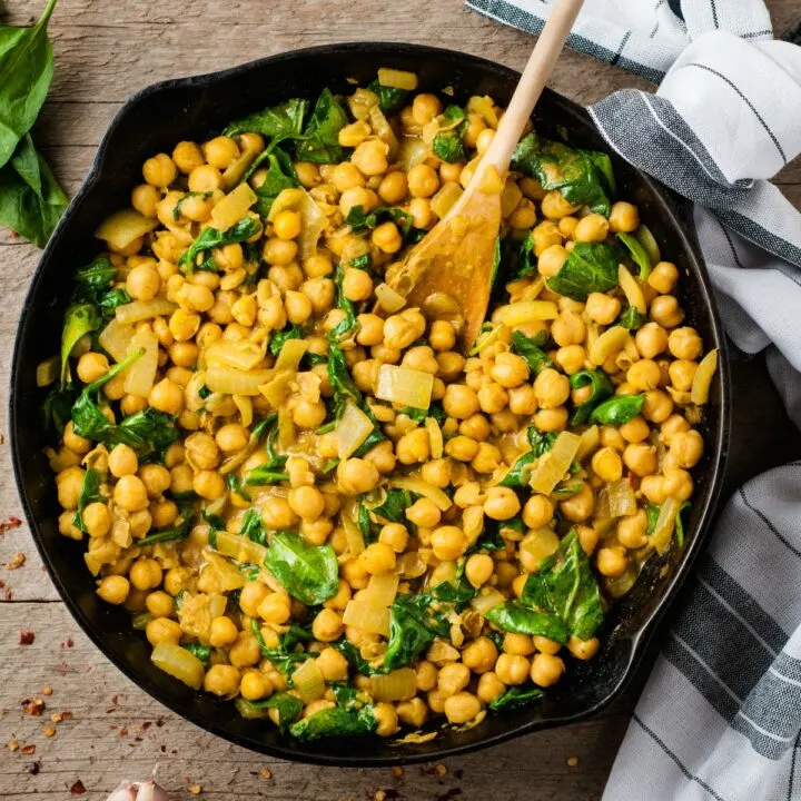 Chickpea curry with spinach in cast iron skillet.