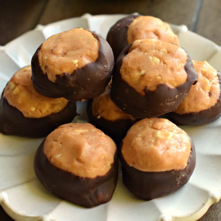 Peanut butter balls on a white scalloped plate.