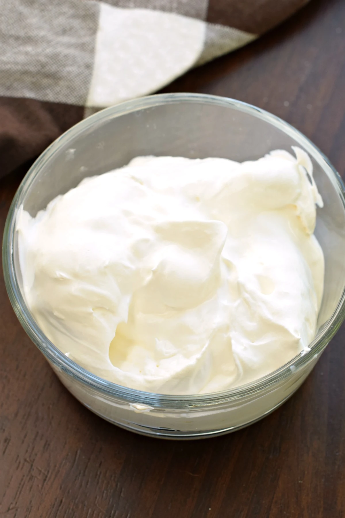 Whipped cream in a clear glass bowl.