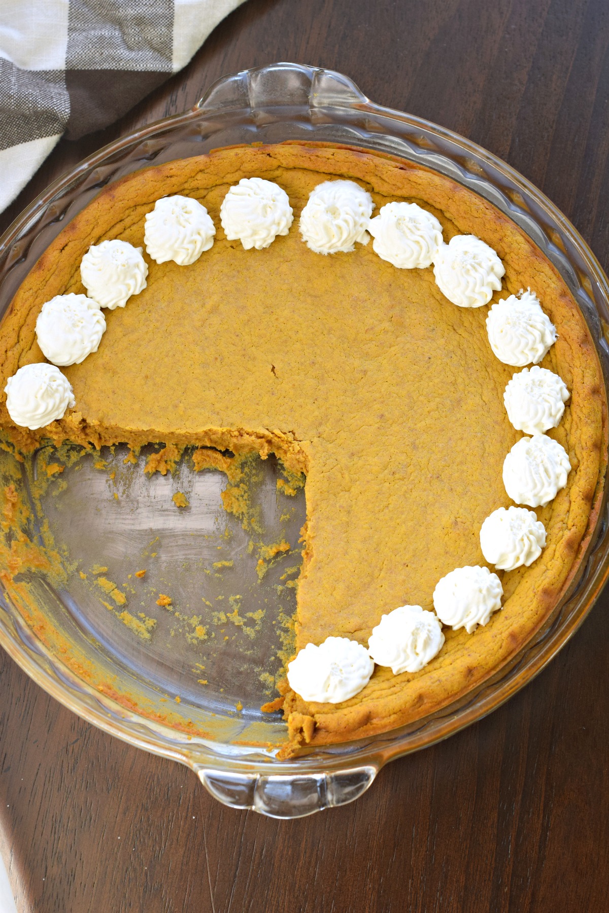 Pumpkin pie with whipped cream in pie plate.