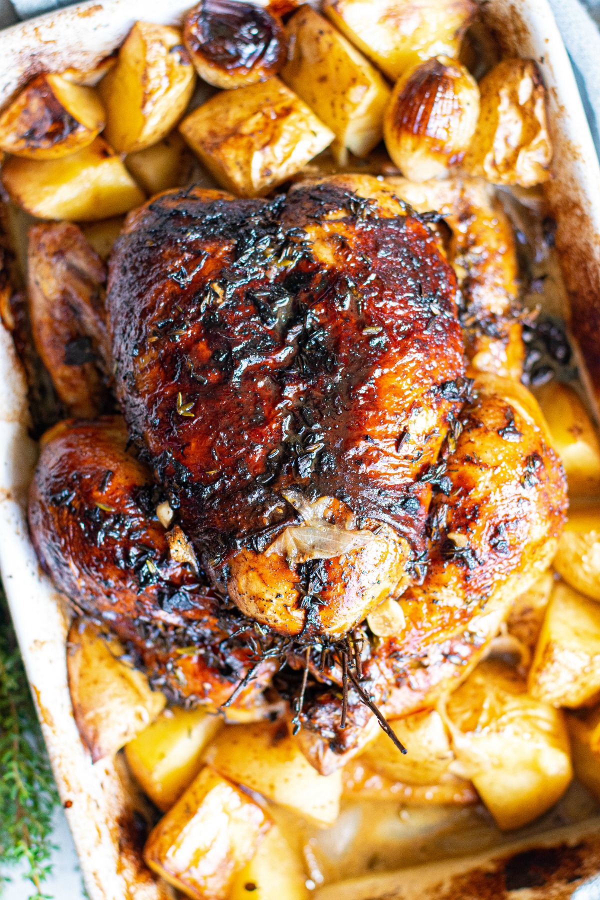 Whole roasted chicken with balsamic glaze in roasting pan.