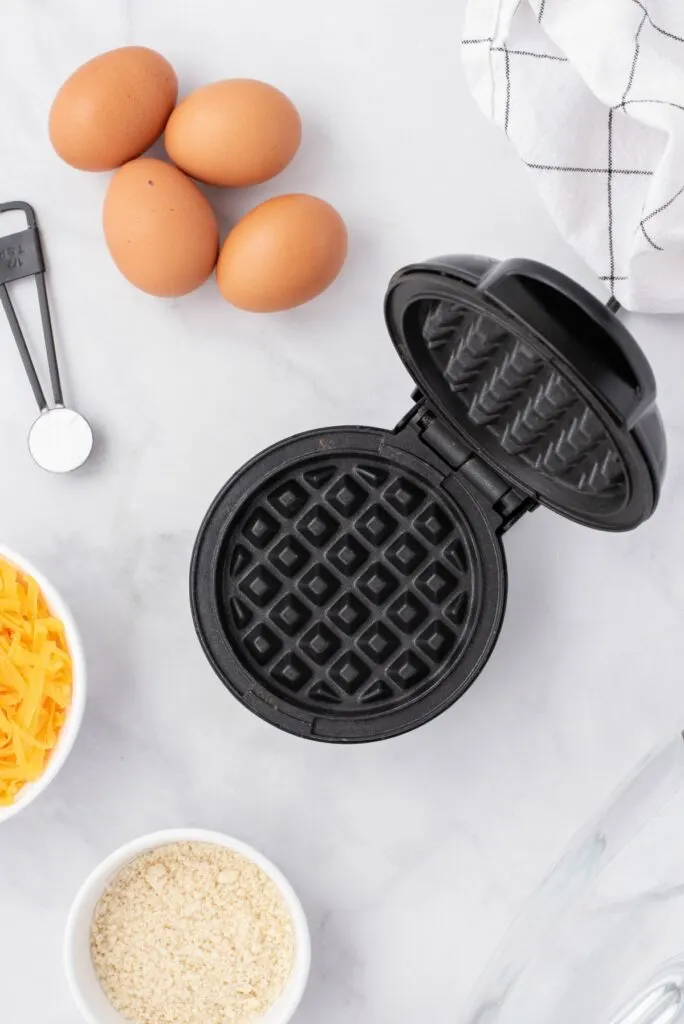 Ingredients needed to make chaffles, including cheese, eggs, and waffle maker.