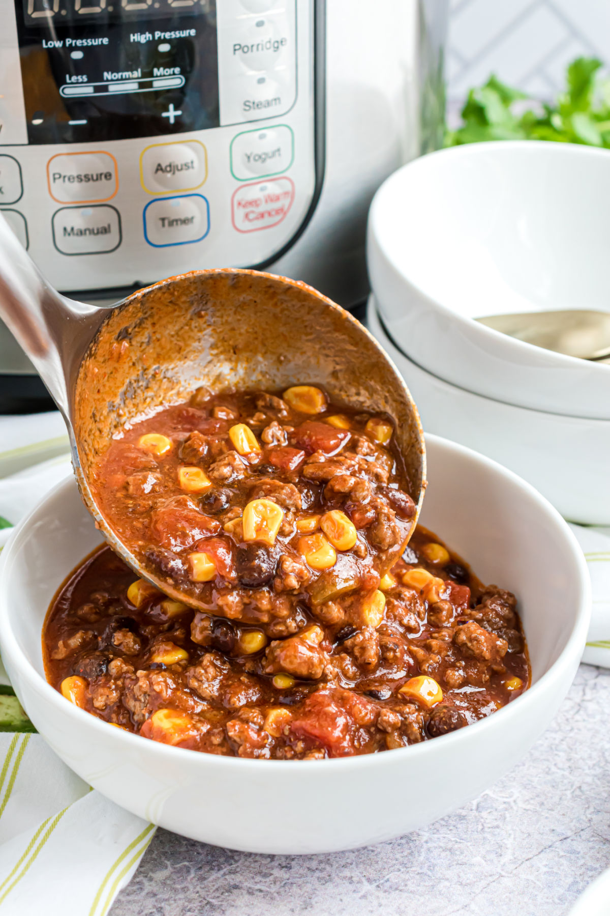 Taco chili made in the pressure cooker and being ladled into a serving bowl.