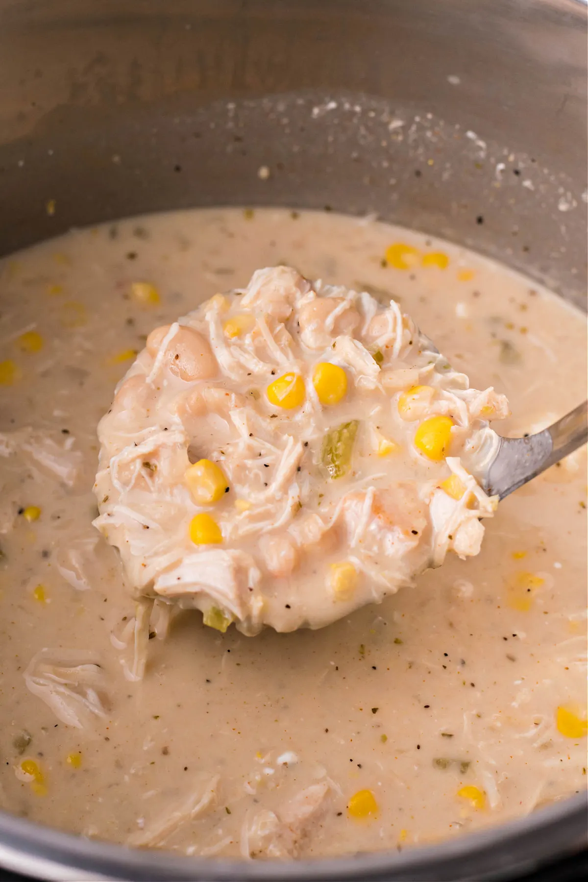 White chicken chili being ladled out of pressure cooker.