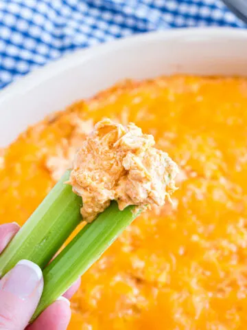 Buffalo chicken dip being scooped with celery.