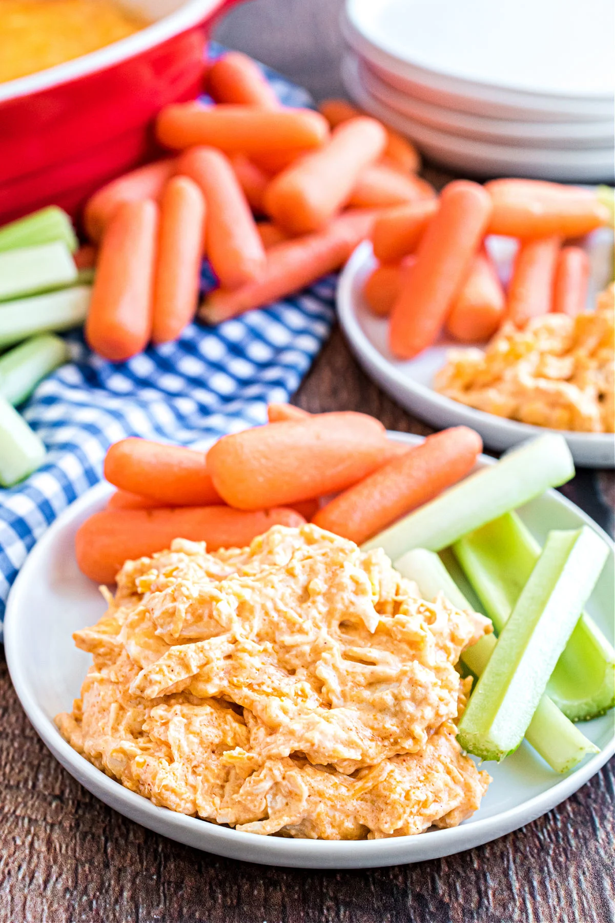 Buffalo chicken dip scooped onto a plate and served with fresh vegetables.