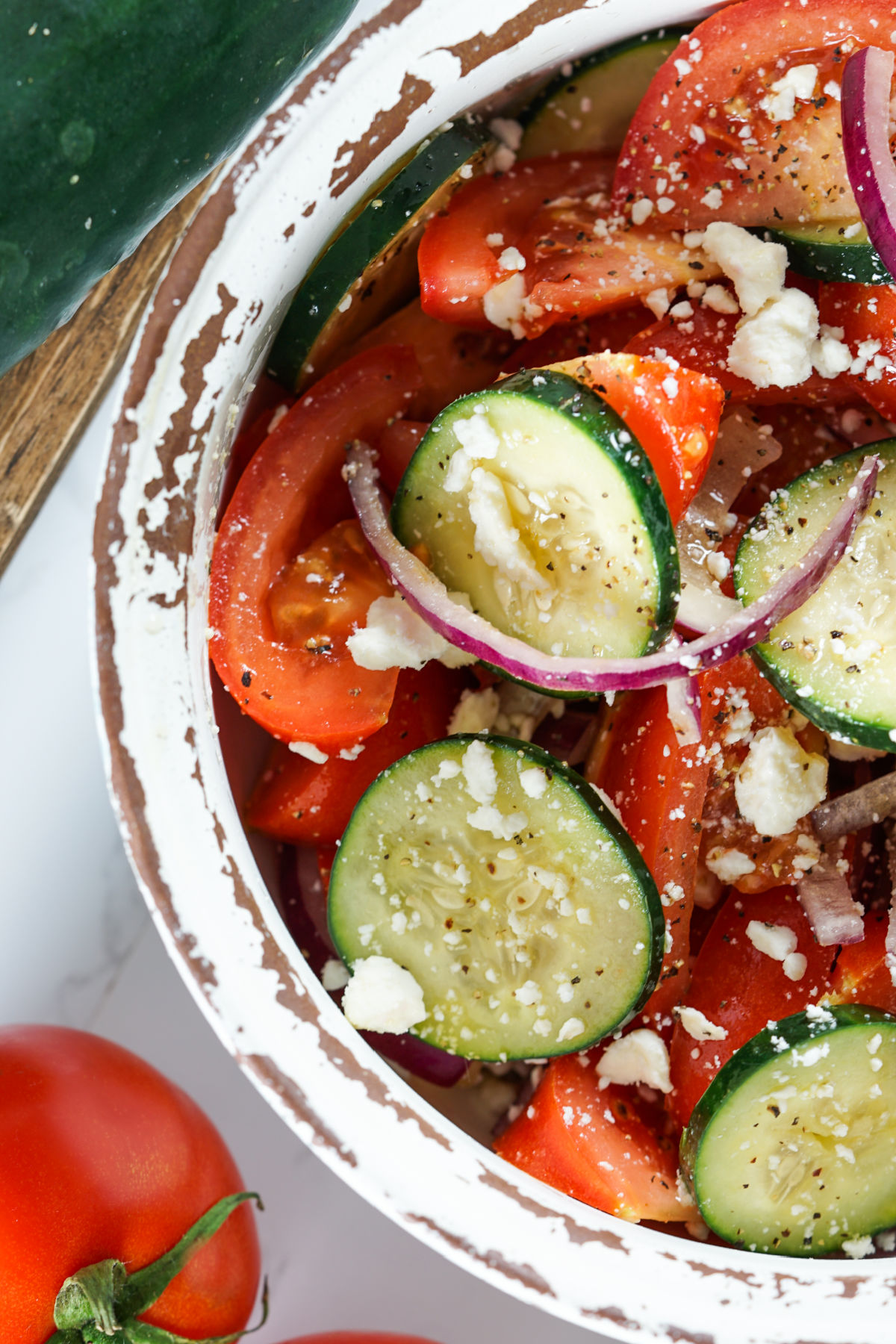 Cucumber tomato salad in a white serving bowl.