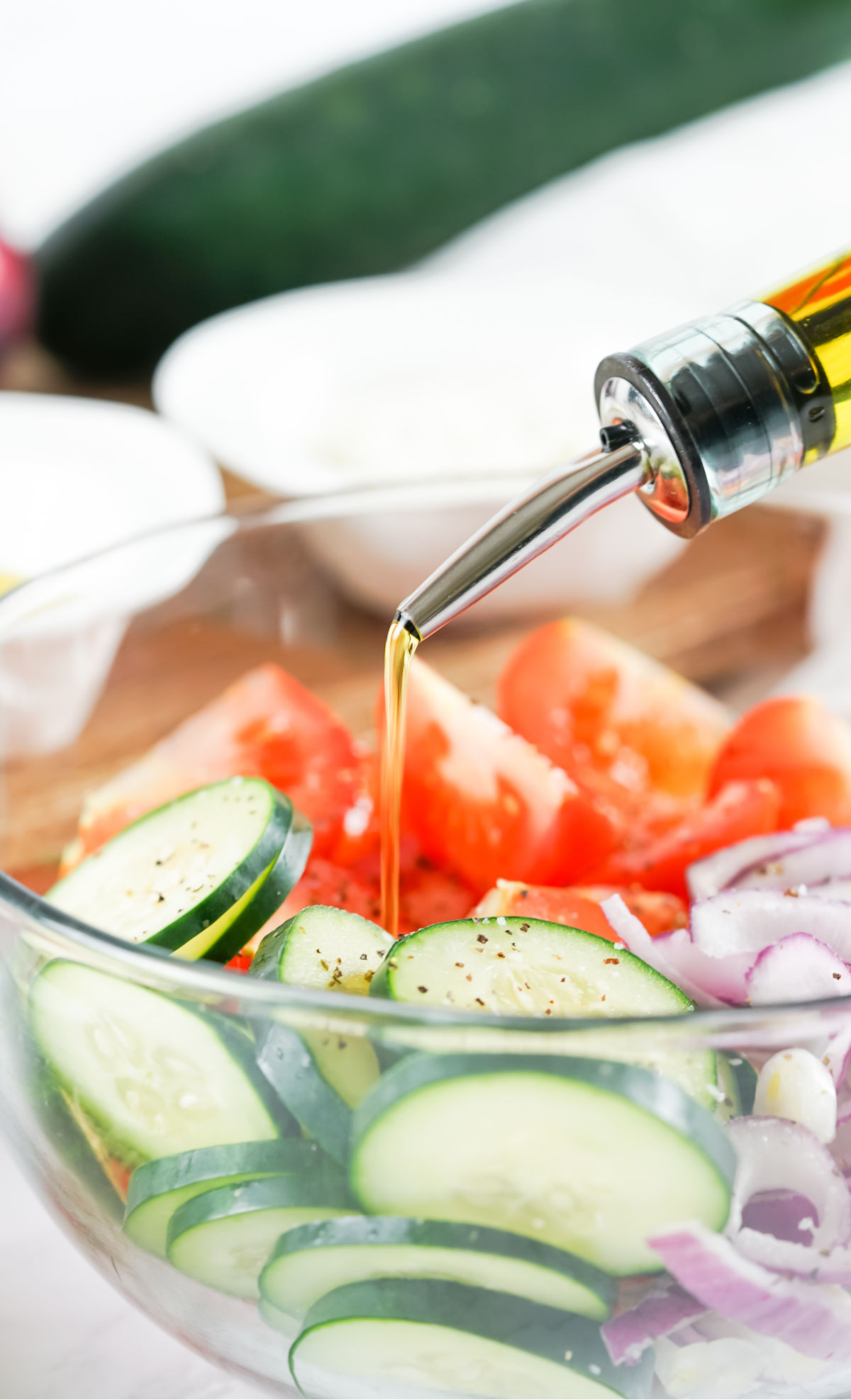Olive oil being drizzled over cucumber salad.