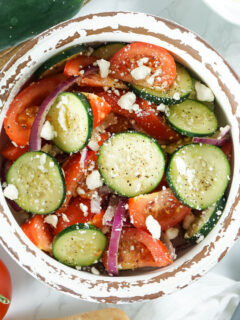Cucumber tomato salad in a bowl with feta cheese.