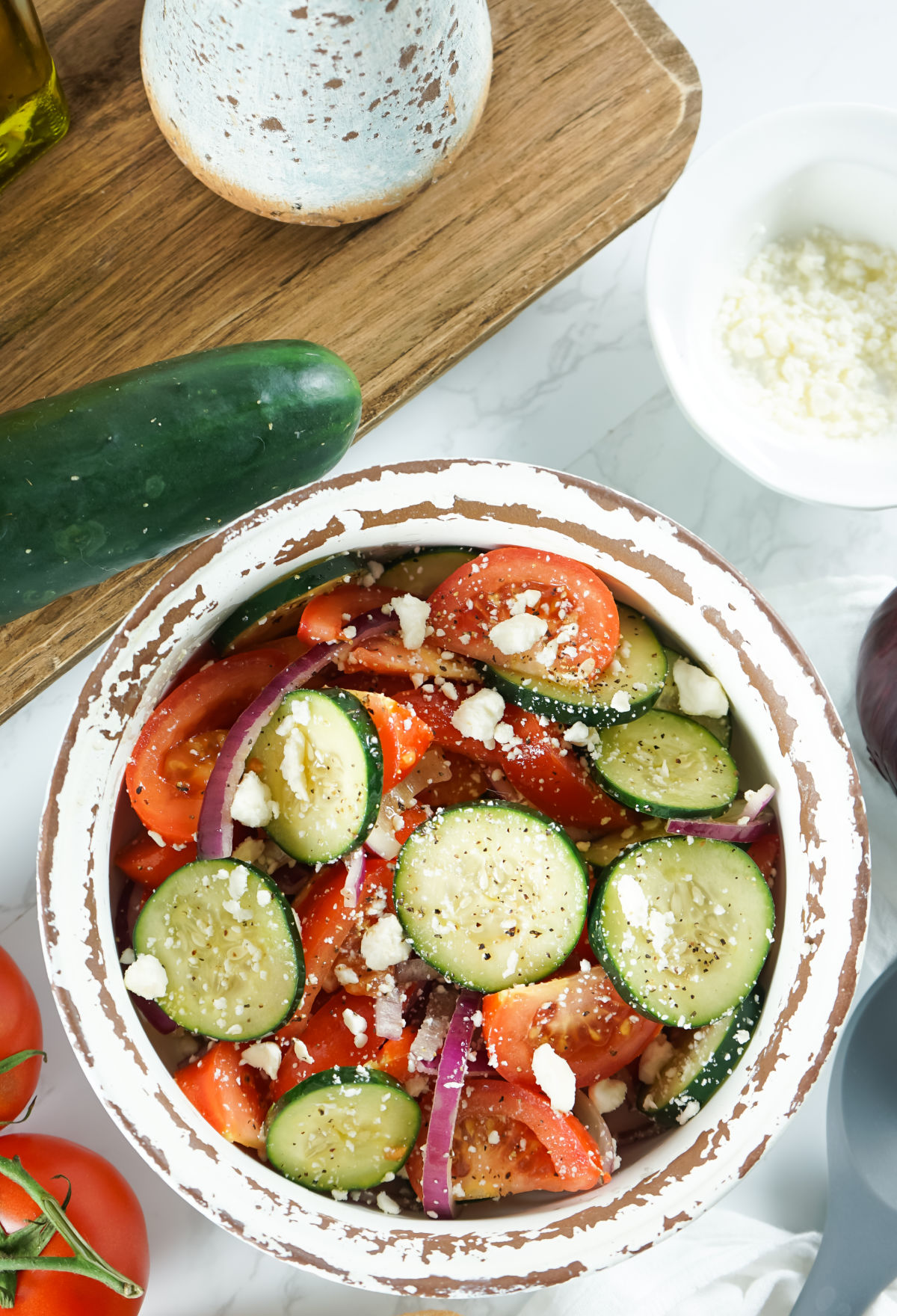 Cucumber tomato salad in a white bowl with feta cheese.