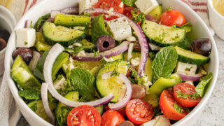 Fresh salad in a white bowl with greek dressing.