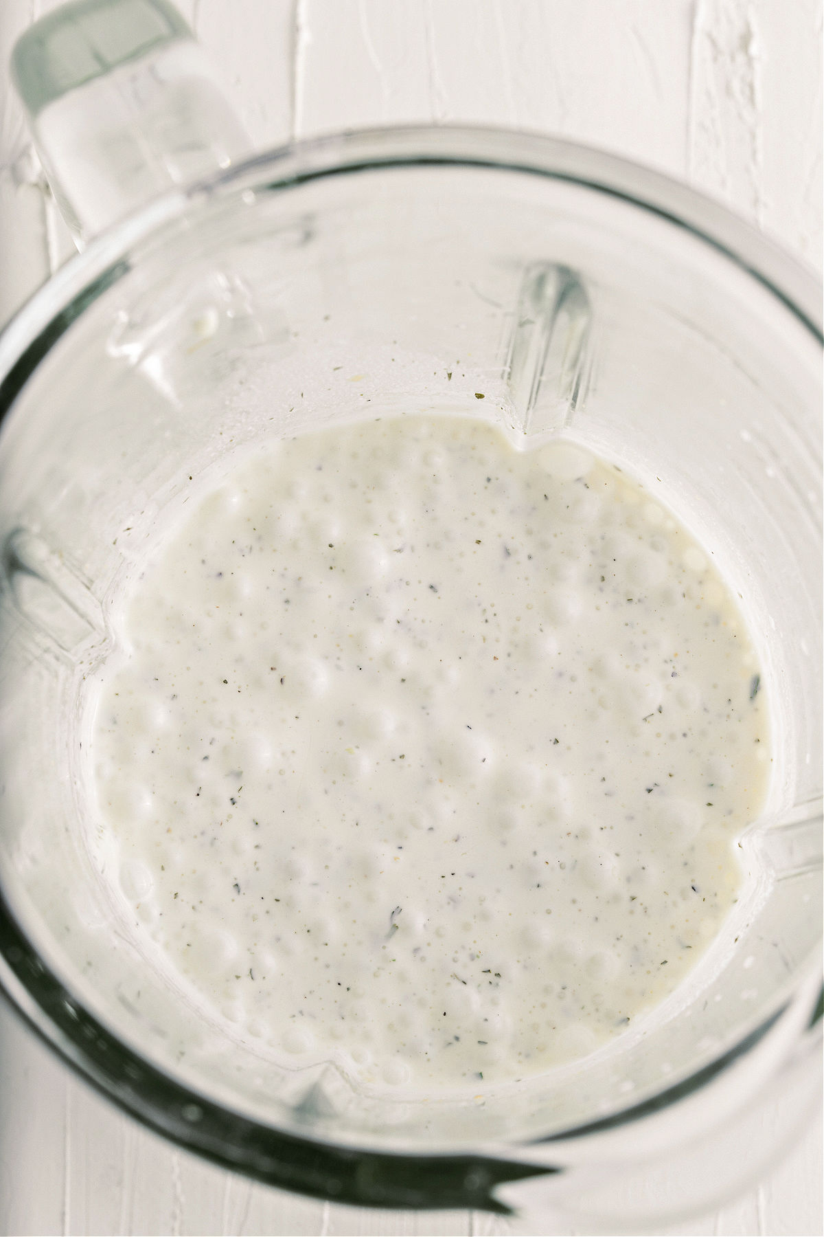 Ranch dressing in a clear glass mixing bowl.