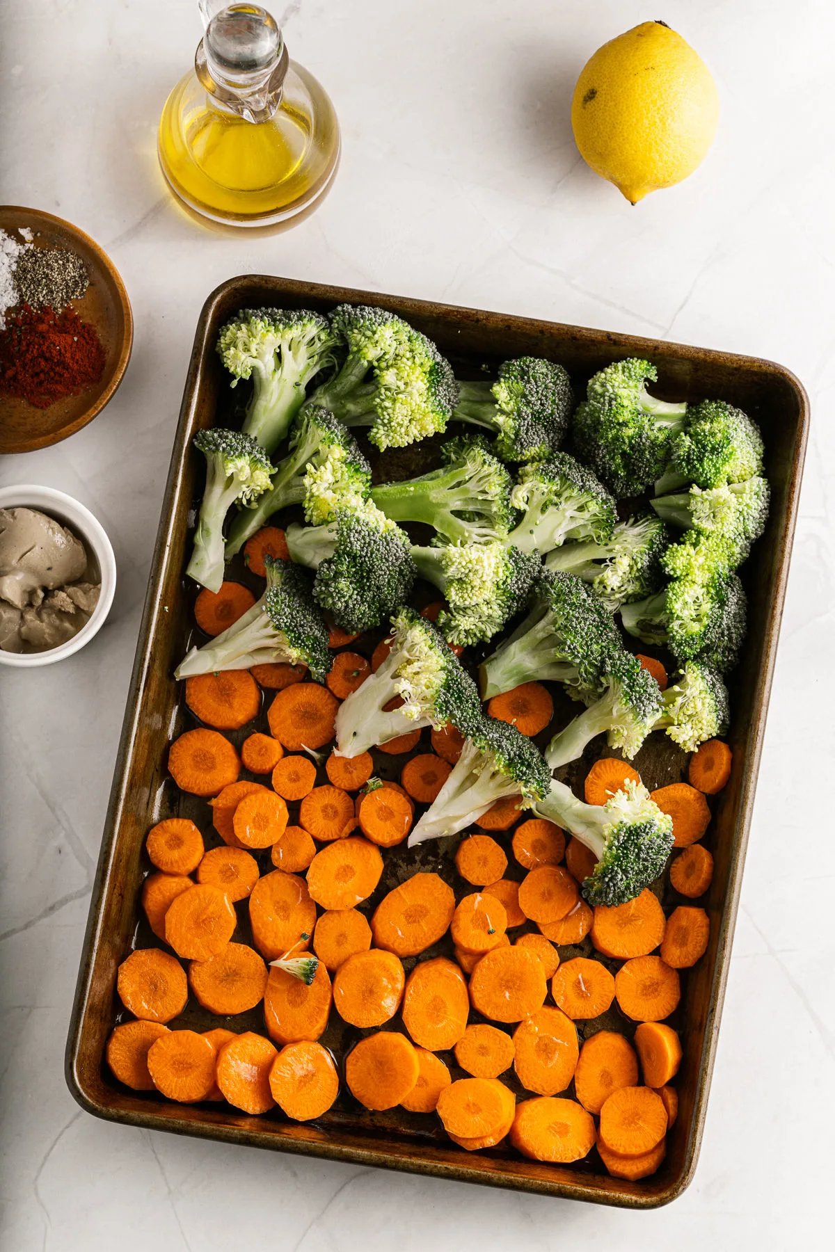 Broccoli and carrot slices on cookie sheet for roasting.