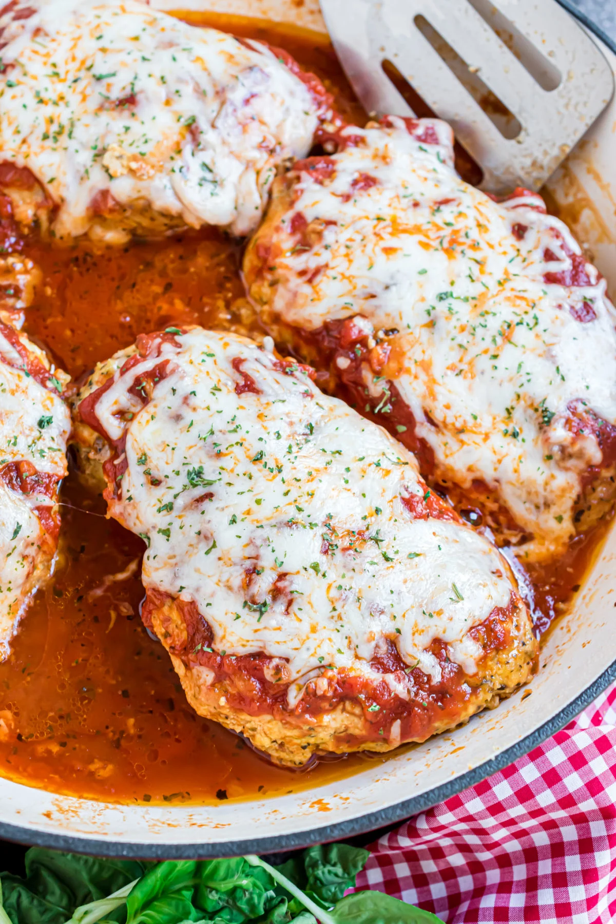 Chicken parmesan in a skillet with sauce and cheese.
