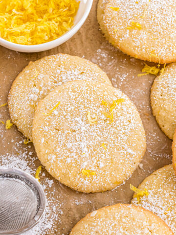 Lemon cookies on parchment paper and dusted with powdered sugar.
