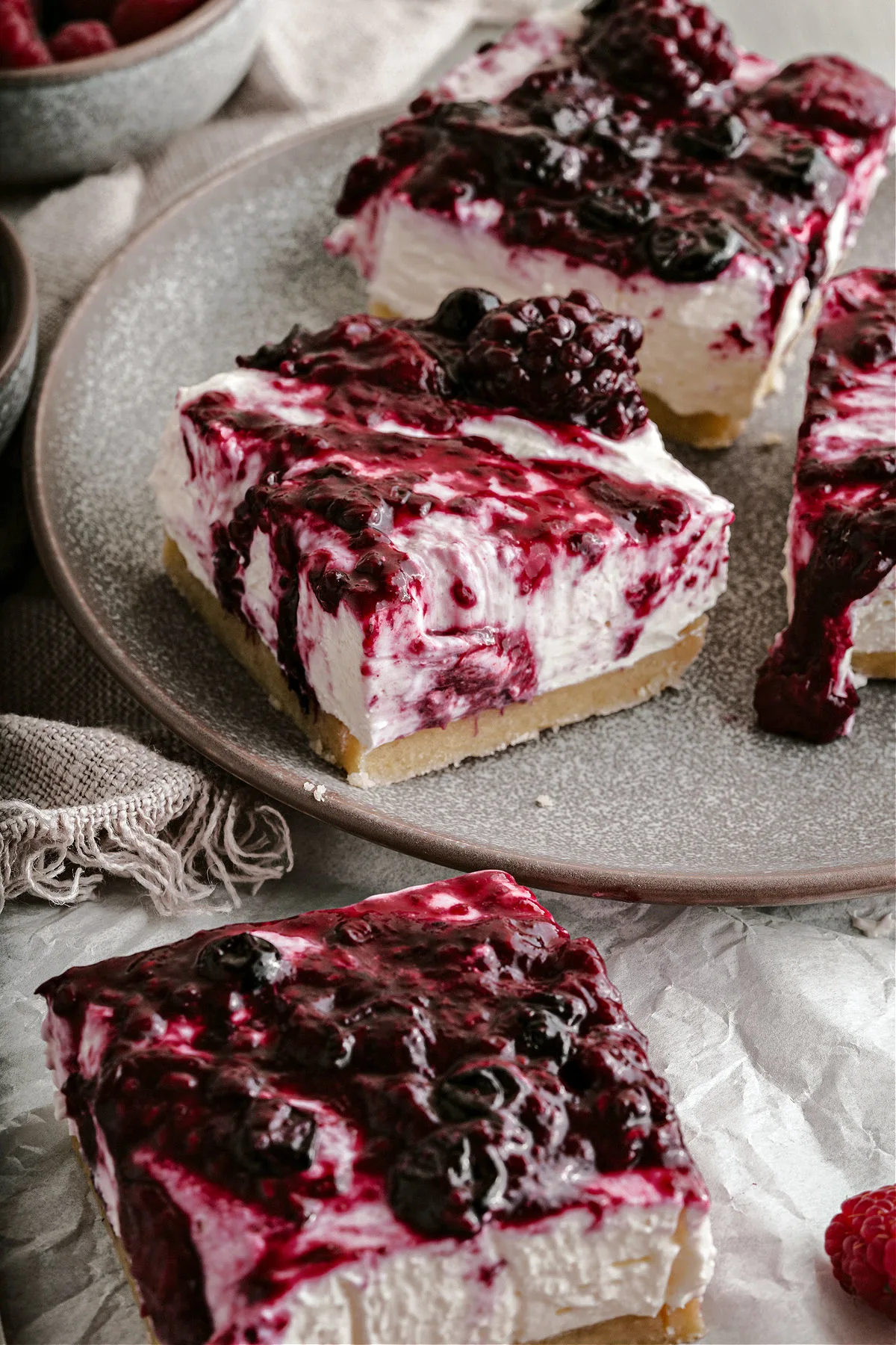 Slices of cheesecake bars on serving plate with berry topping.
