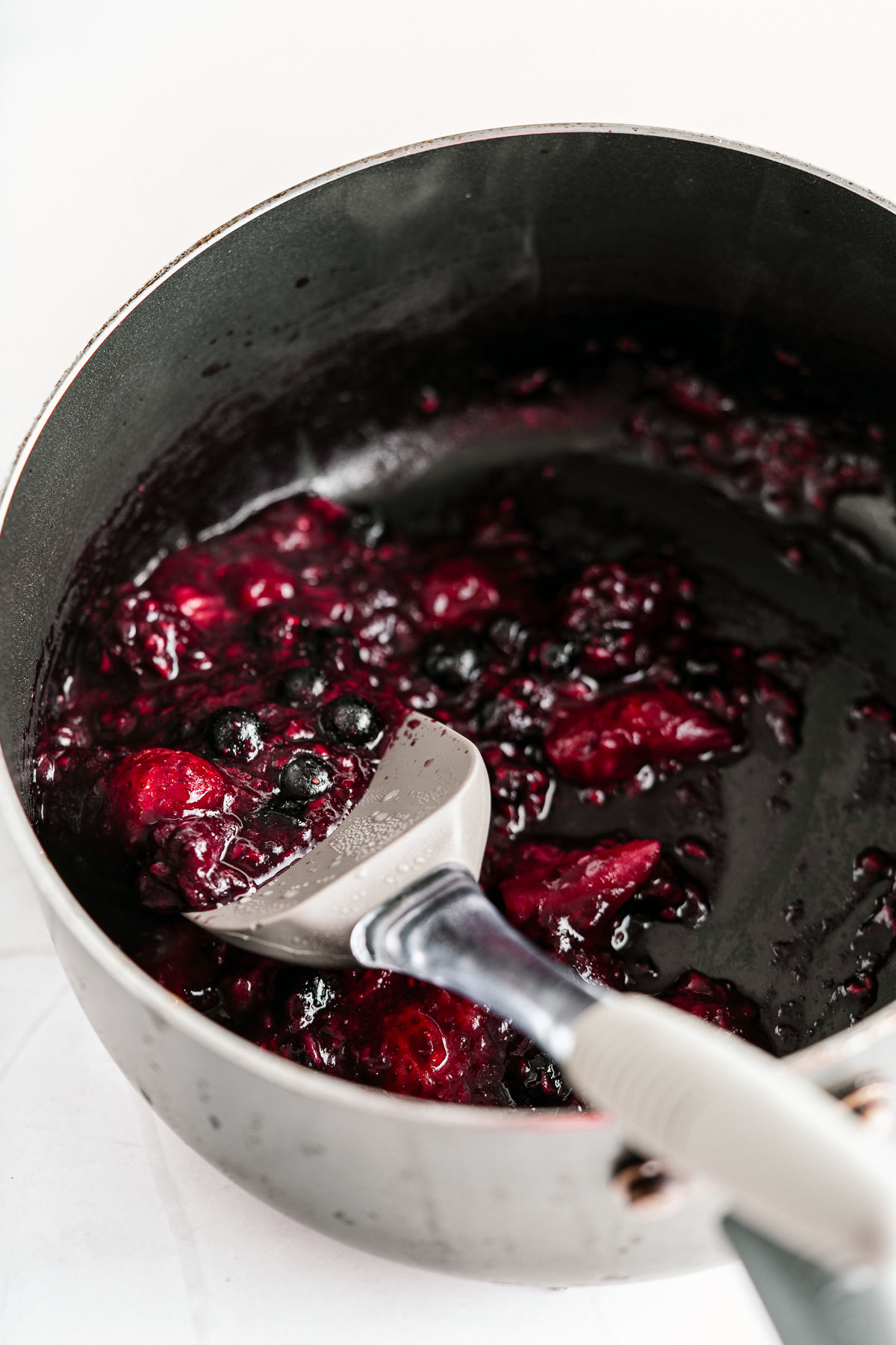 Berry topping for cheesecake bars in a small saucepan.