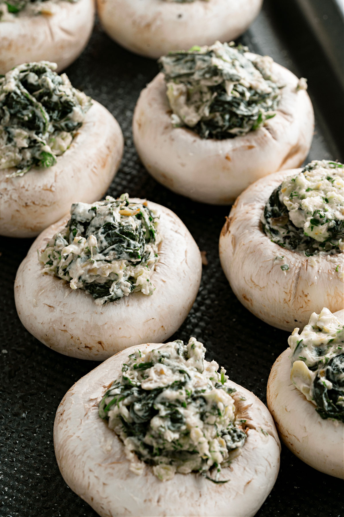 Stuffed mushrooms before baking on a cookie sheet.