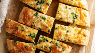 Keto gluten free garlic bread on parchment paper cut into rectangles.