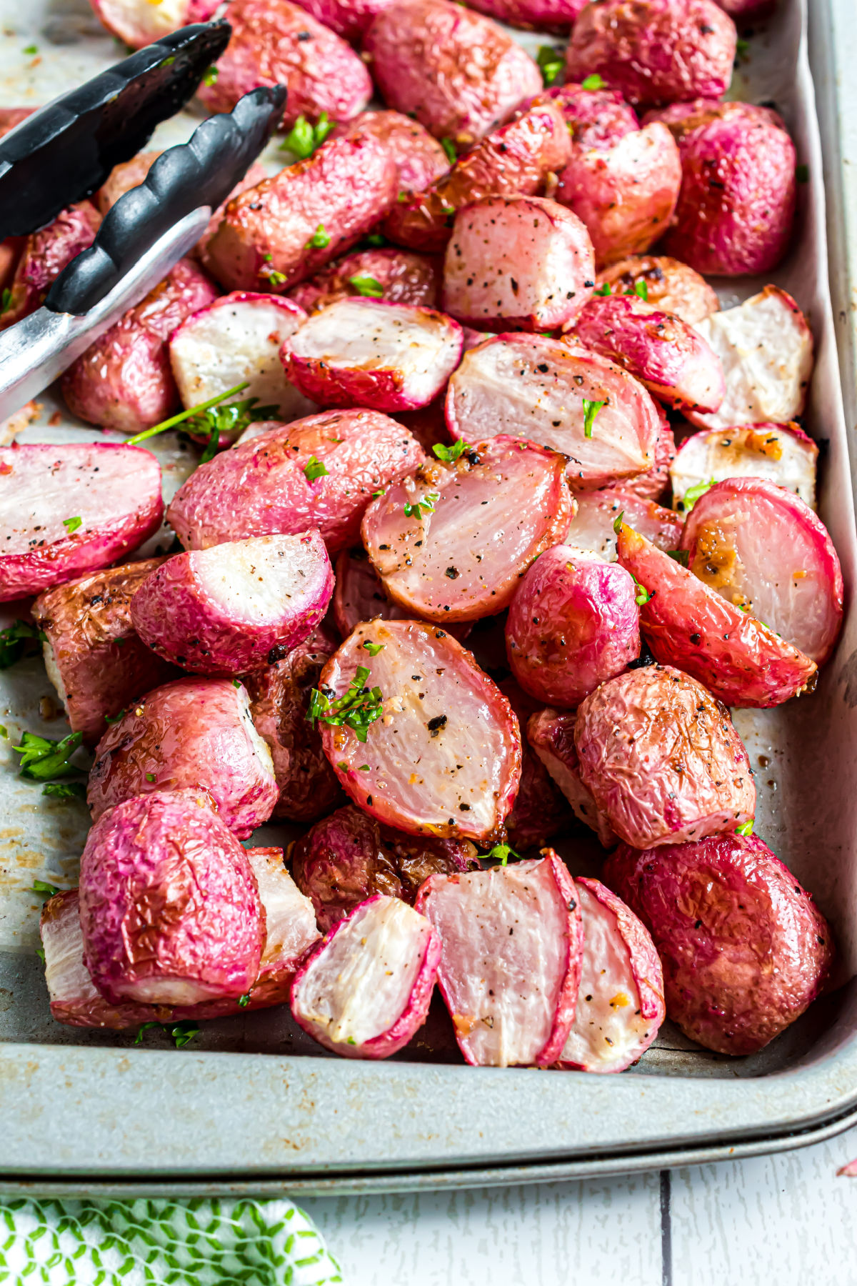 Roasted radishes with garlic and herbs on a cookie sheet.