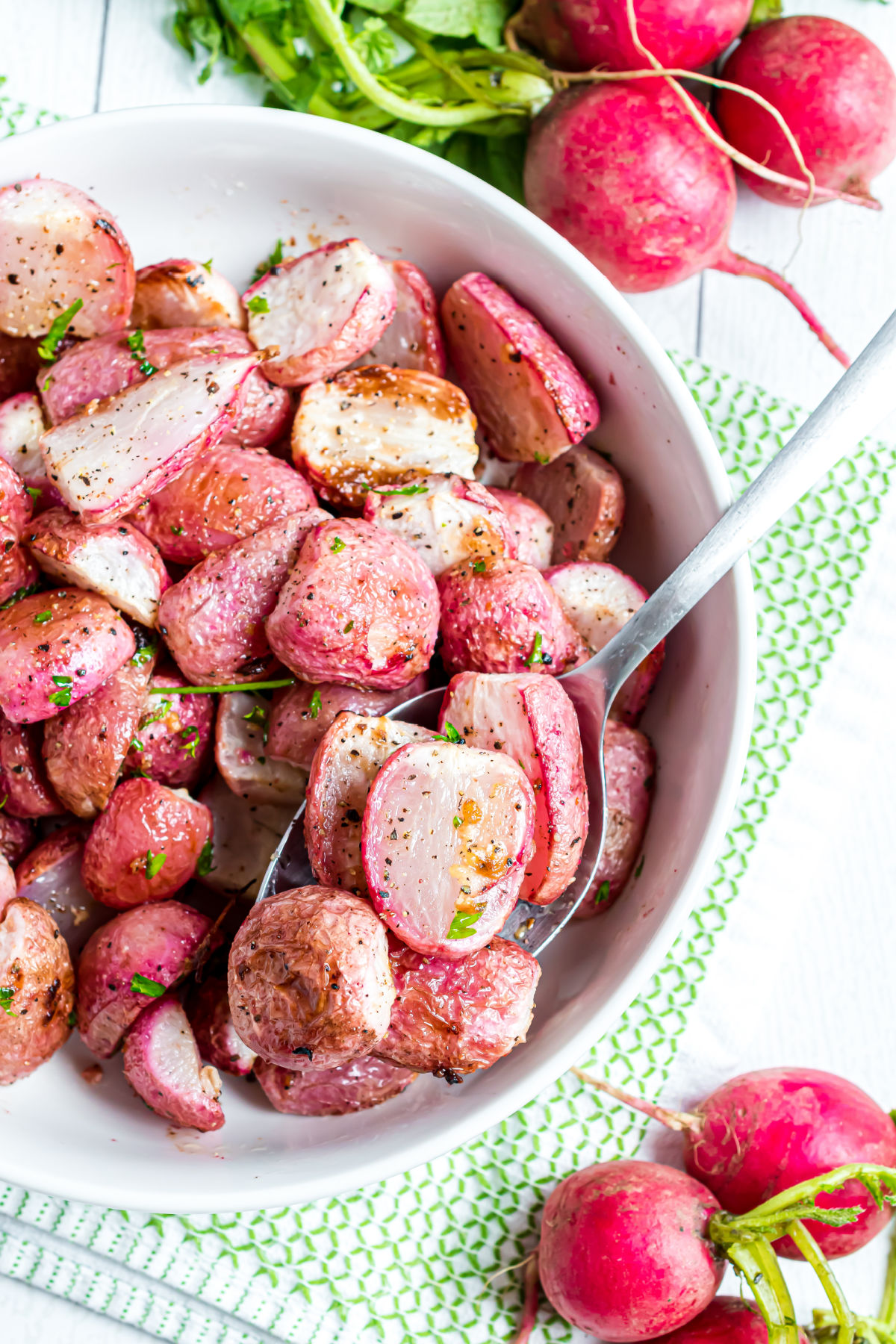 Roasted radishes served in a white bowl.