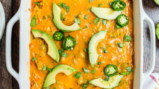 Enchilada casserole with chicken, cheese, and avocados in a baking dish.