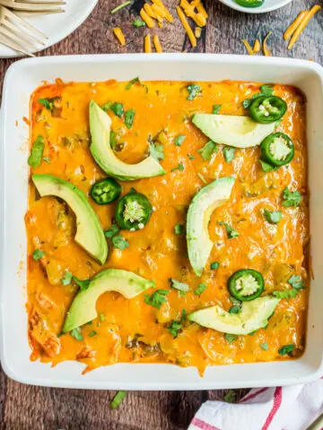 Enchilada casserole with chicken, cheese, and avocados in a baking dish.