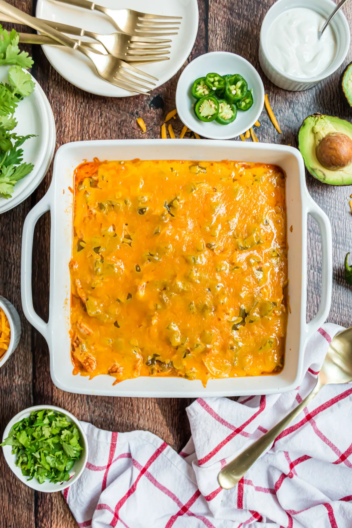 Enchilada casserole baked in a square dish served with jalapenos and sour cream.