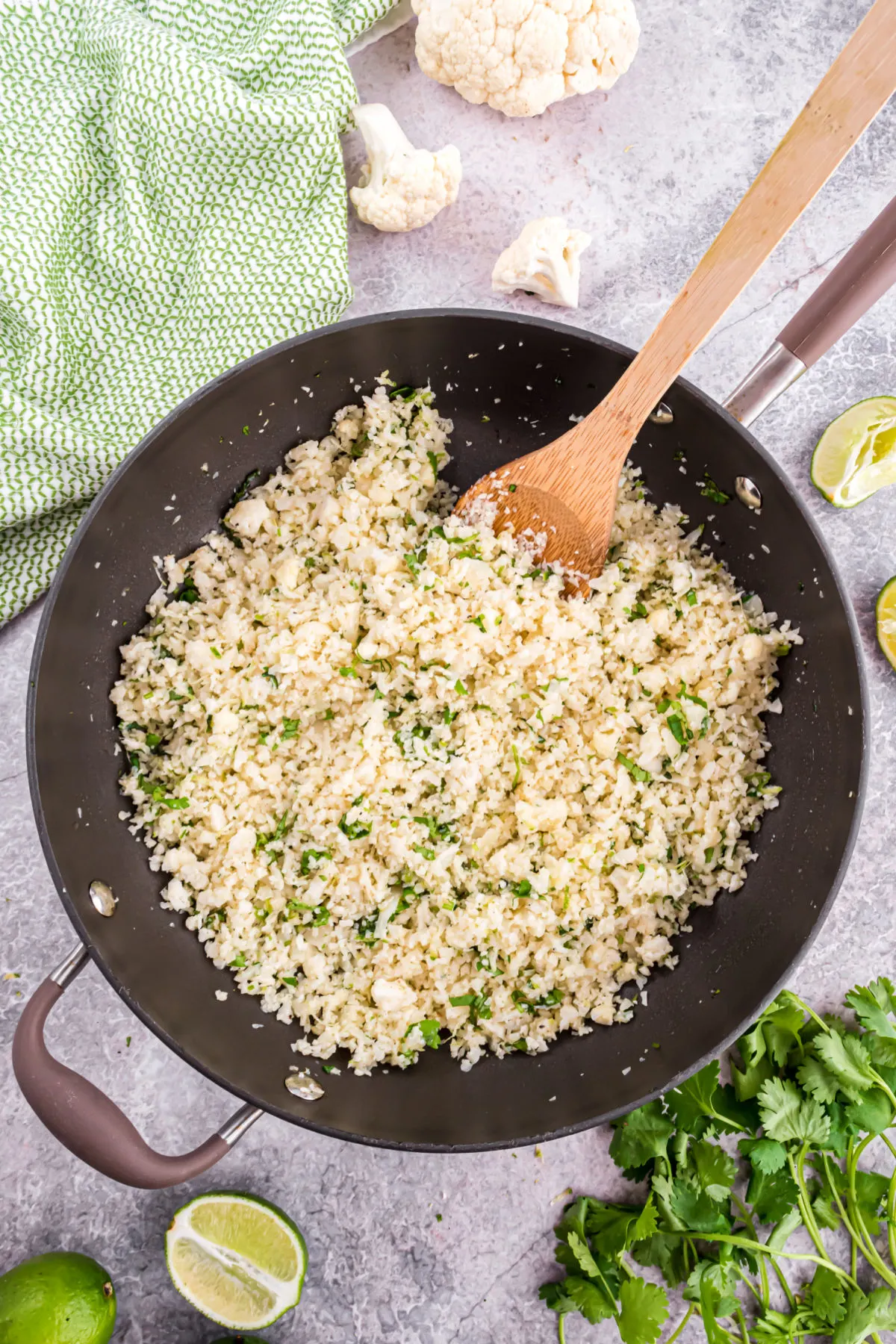 Skillet cooking cauliflower rice with cilantro and lime juice.