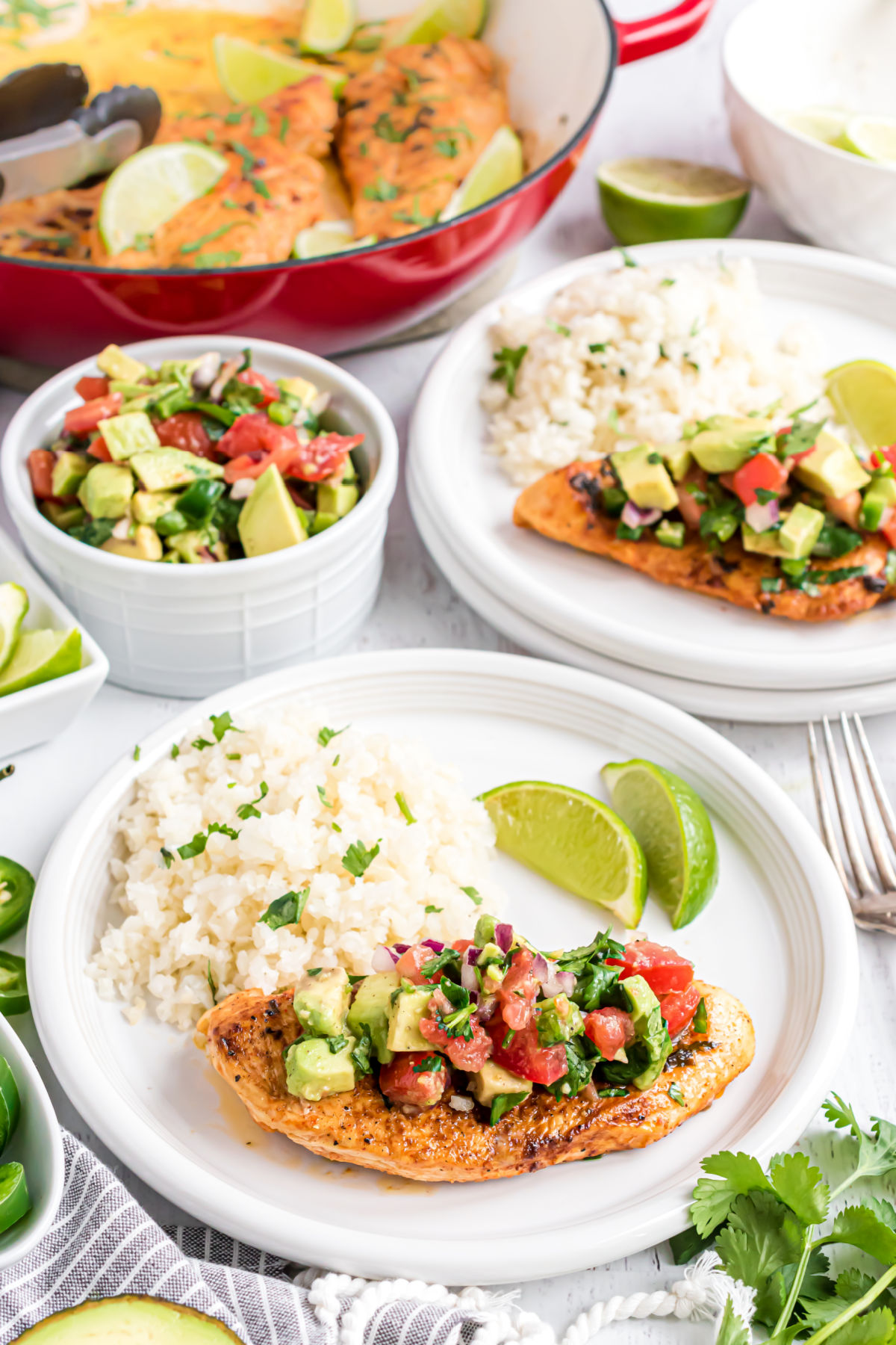 Chicken topped with avocado salsa on a plate with cilantro lime cauliflower rice.