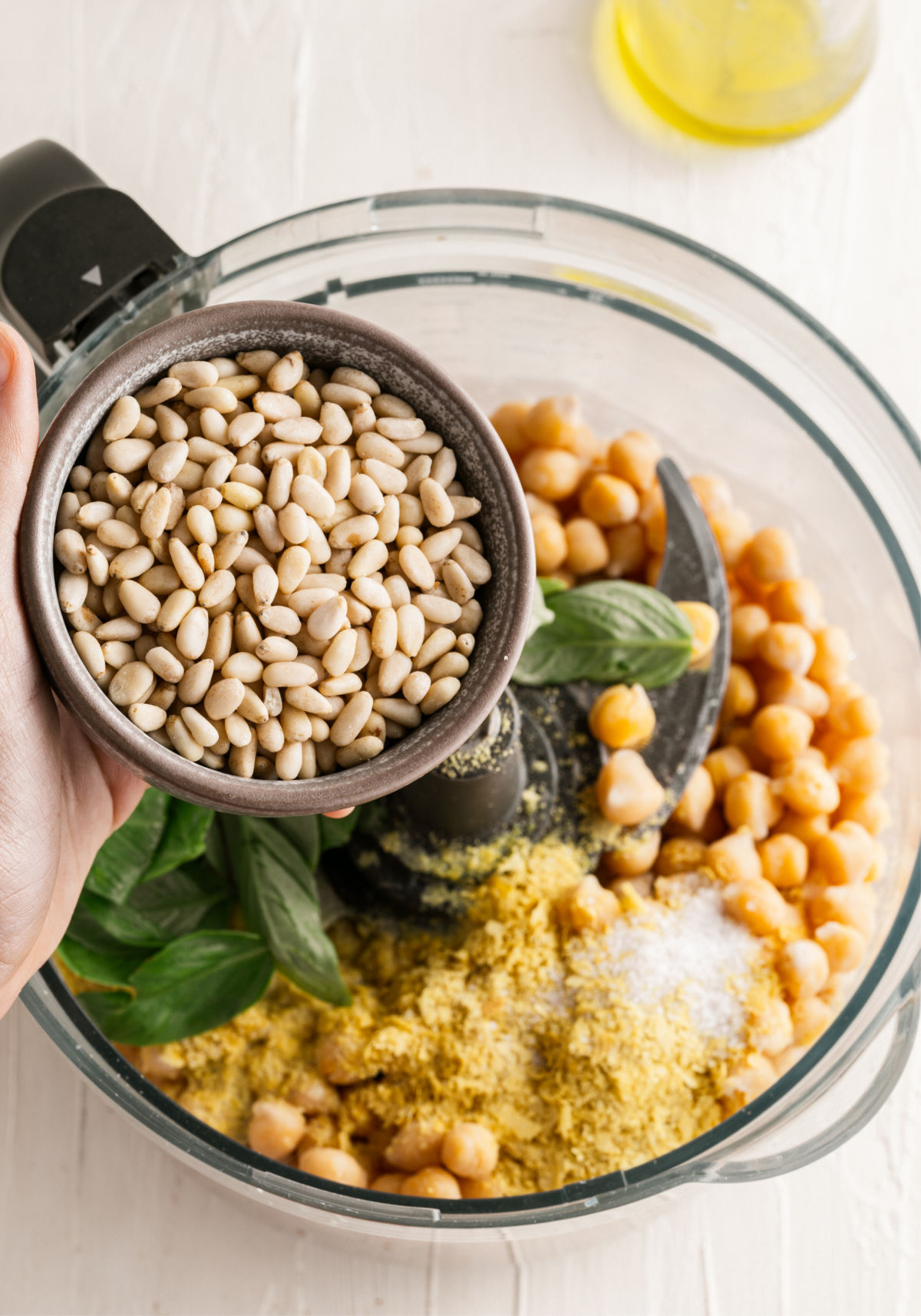 Ingredients being added to food processor for pesto hummus.