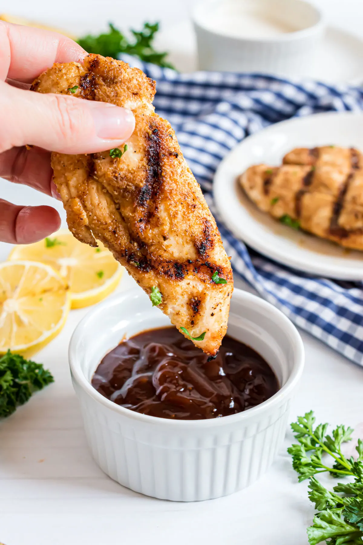 Grilled chicken tenders being dipped in bbq sauce with no sugar.