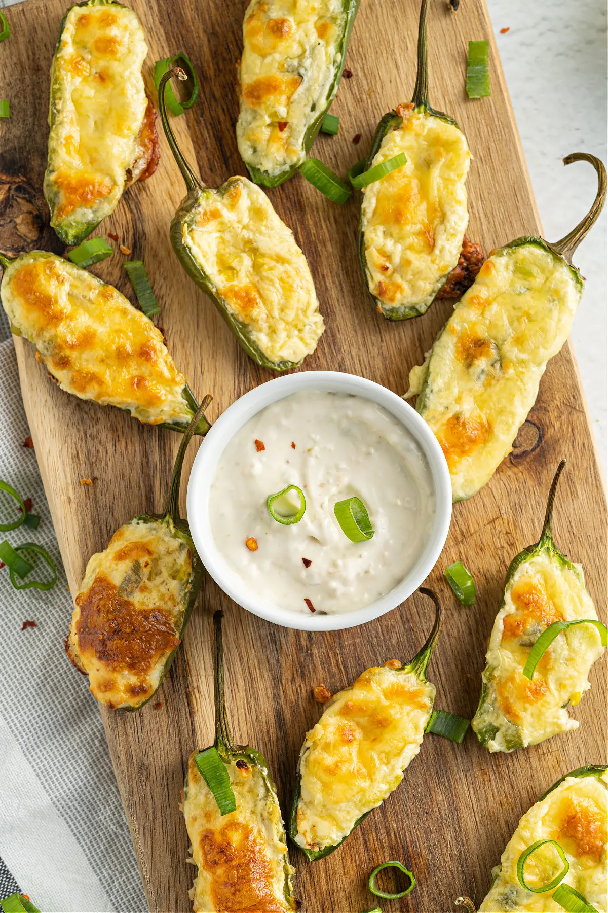 Serving tray with cheesy jalapeno poppers and bowl of ranch dressing.