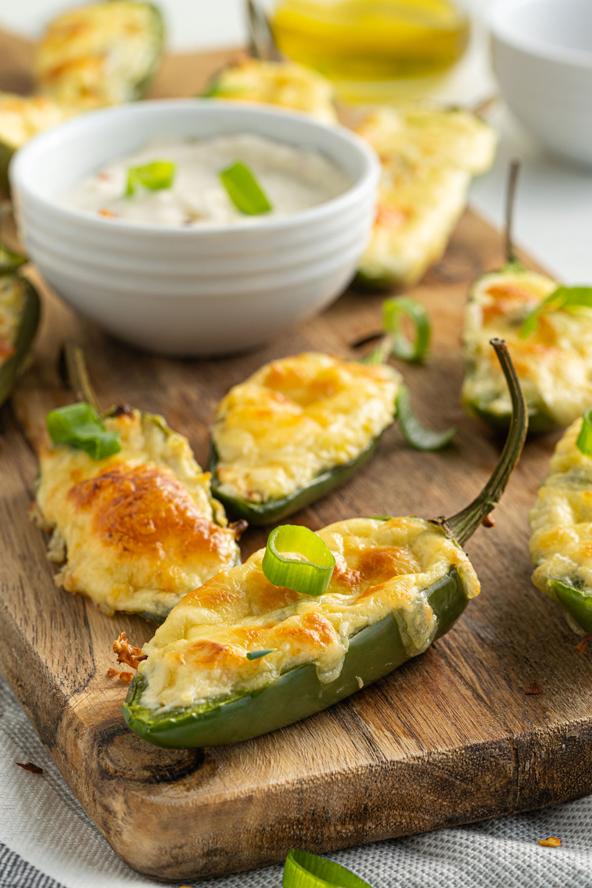 Baked jalapeno poppers on a wooden cutting board with a bowl of ranch,