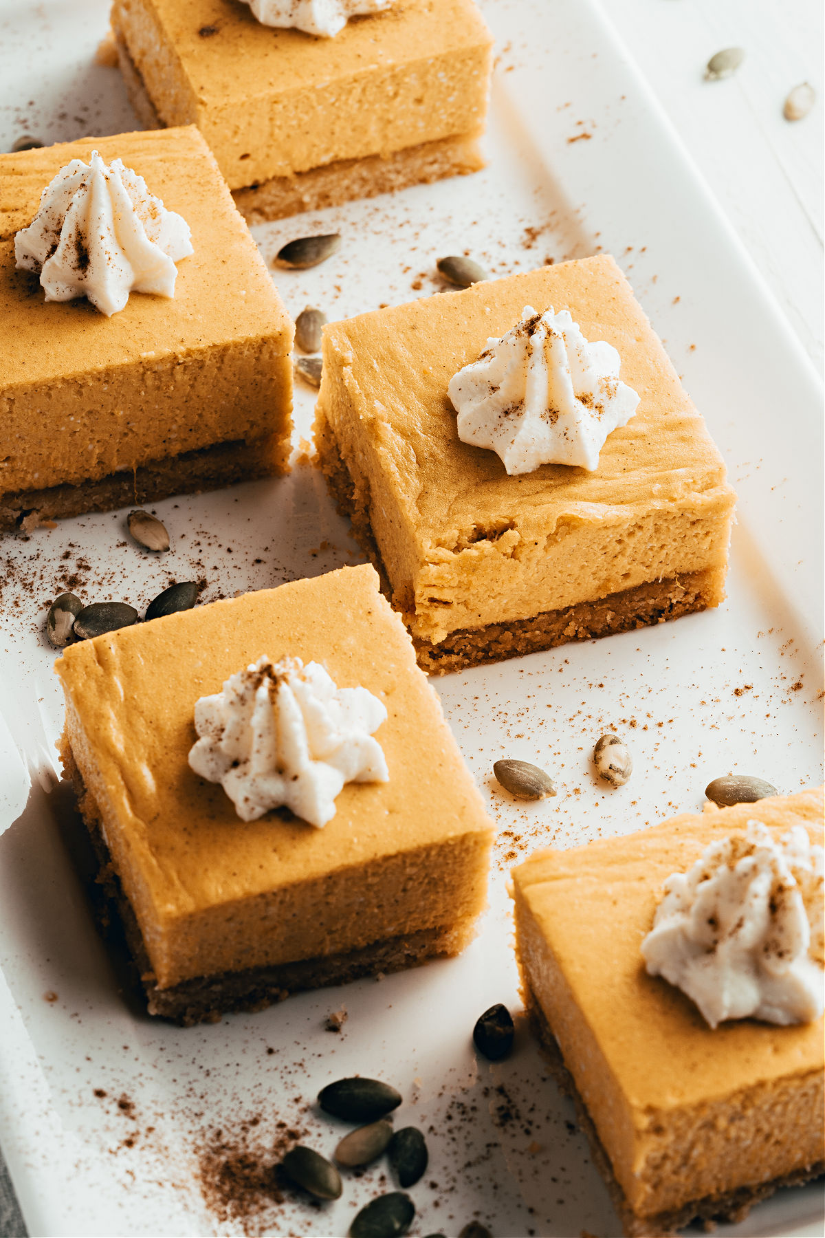 Squares of pumpkin cheesecake on serving plate.