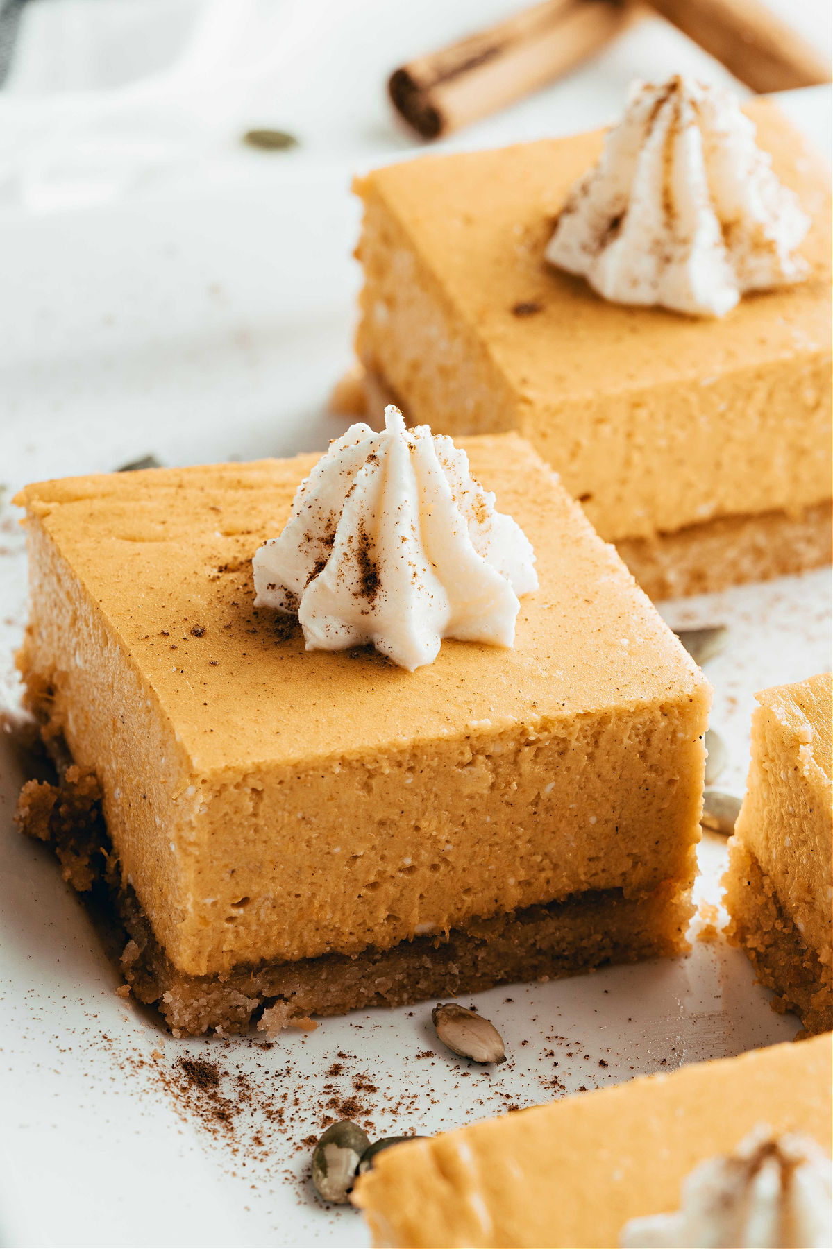 Pumpkin cheesecake bars with a dollop of whipped cream on top.