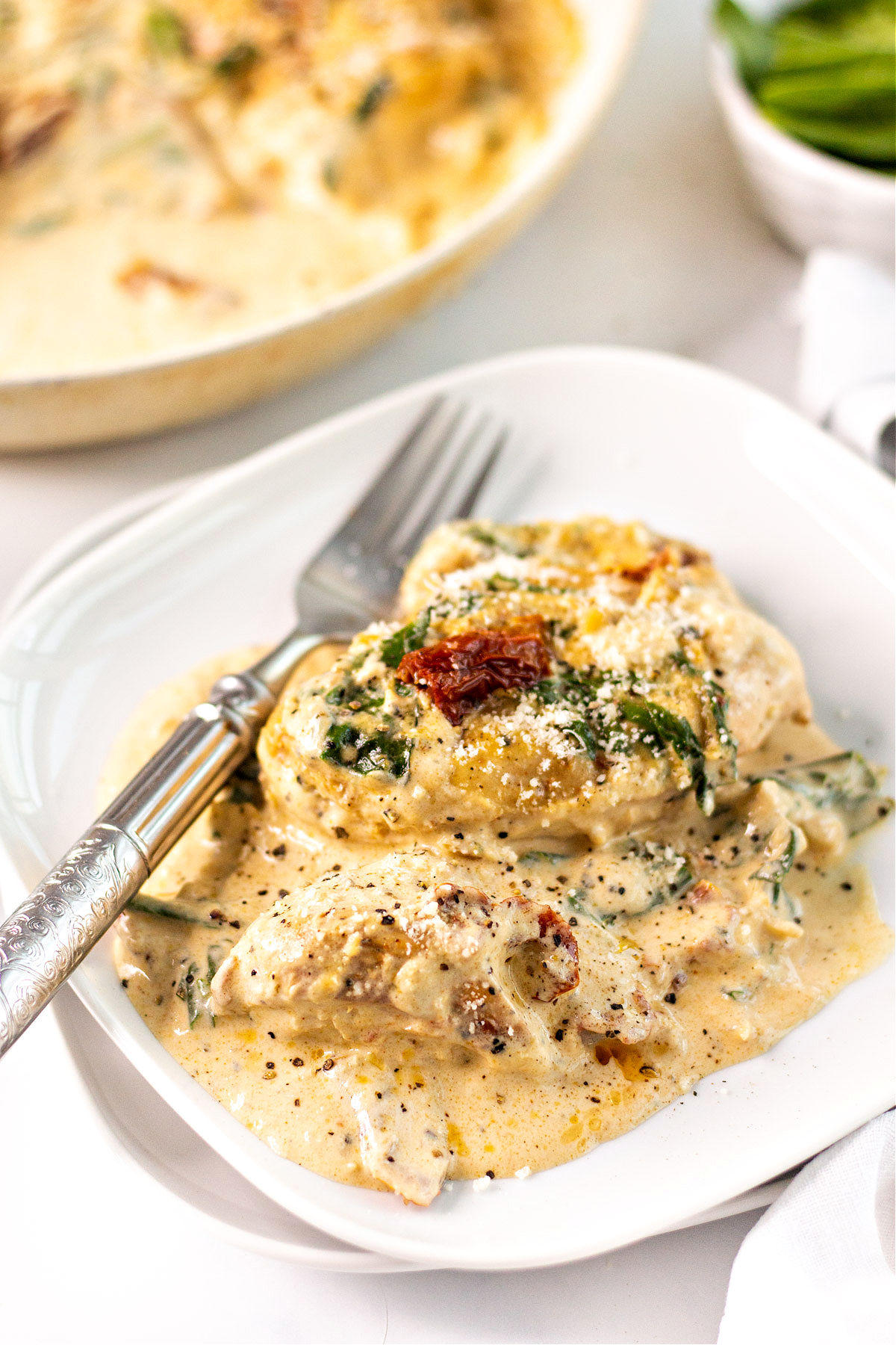 Chicken in creamy spinach sauce served on a white plate.