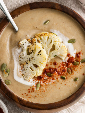 Served bowl of cauliflower soup with garnished on top.