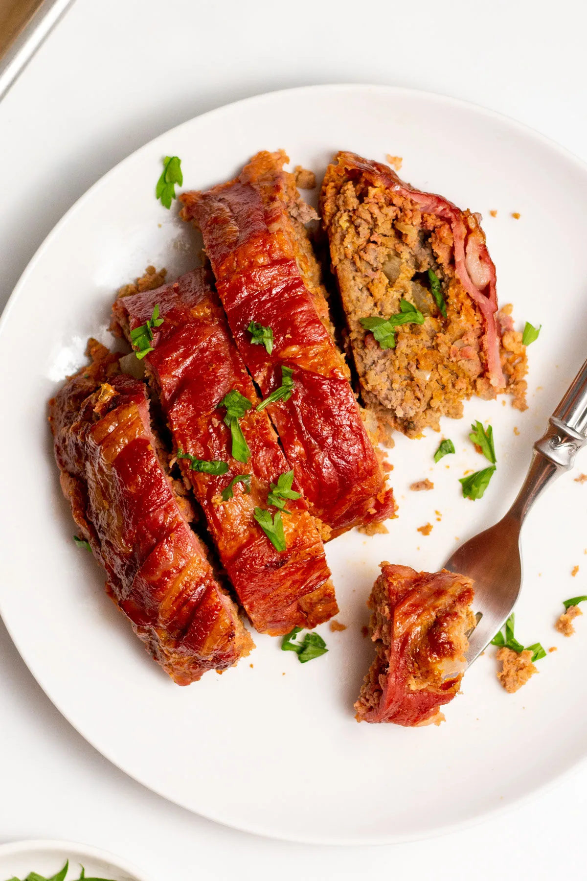 white plate with bacon wrapped meatloaf slices.