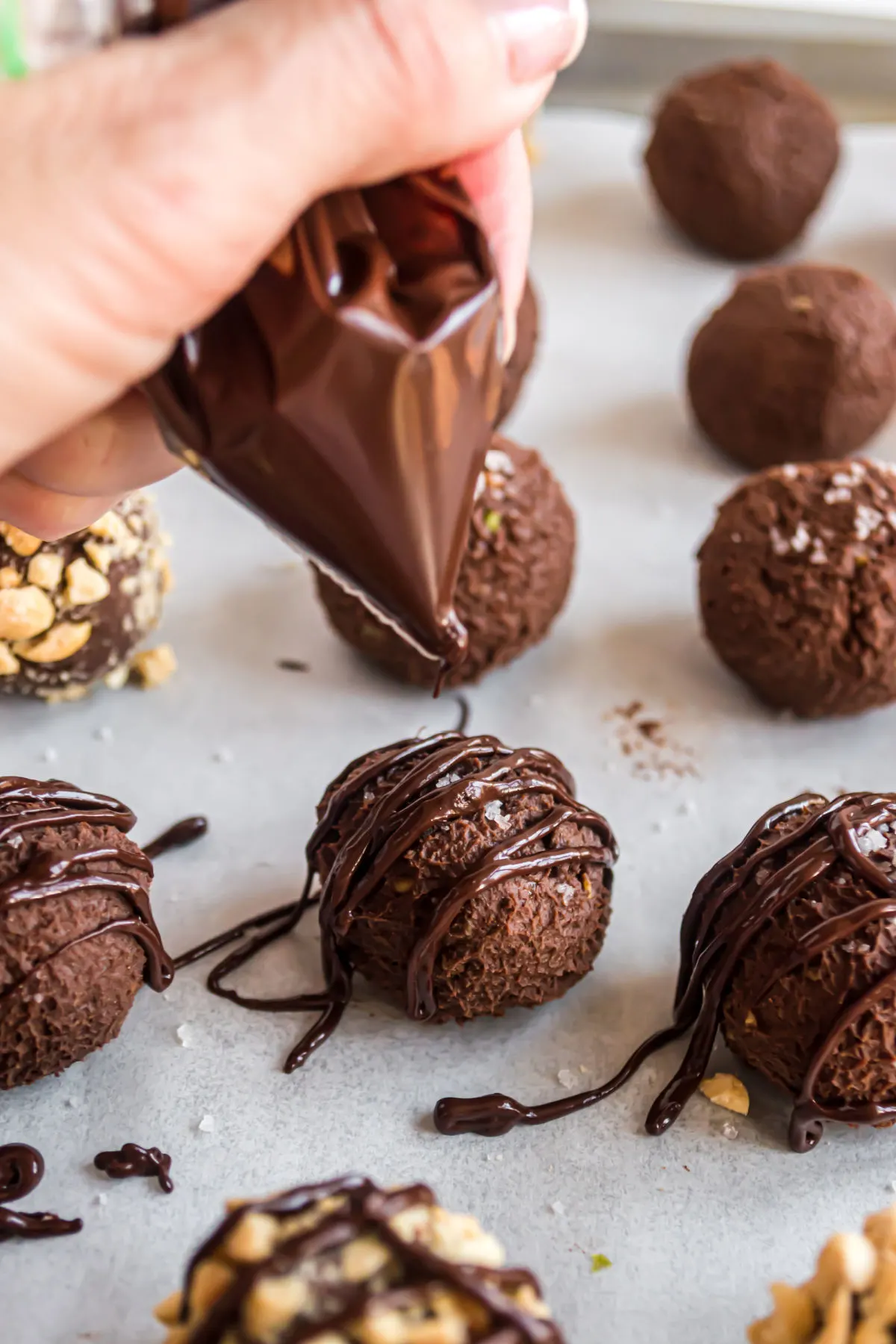 Melted sugar free chocolate in a ziploc bag being drizzled over avocado truffles.