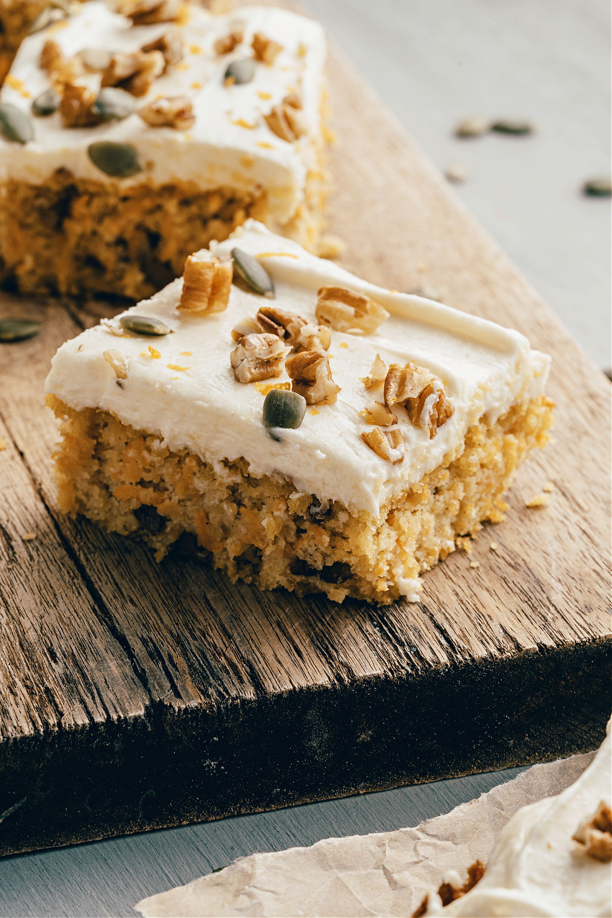 Two slices of carrot cake on wooden serving board.