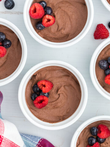 Sugar free chocolate pudding in ramekins with berries on top.