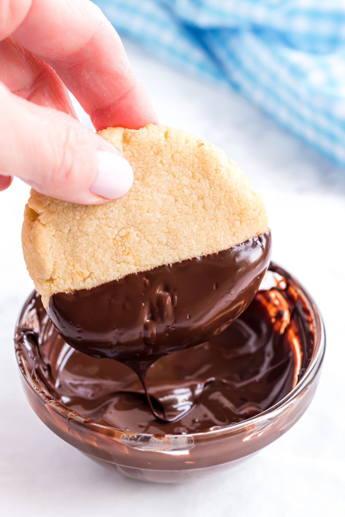 Shortbread cookies being dipped in sugar free melted chocolate.