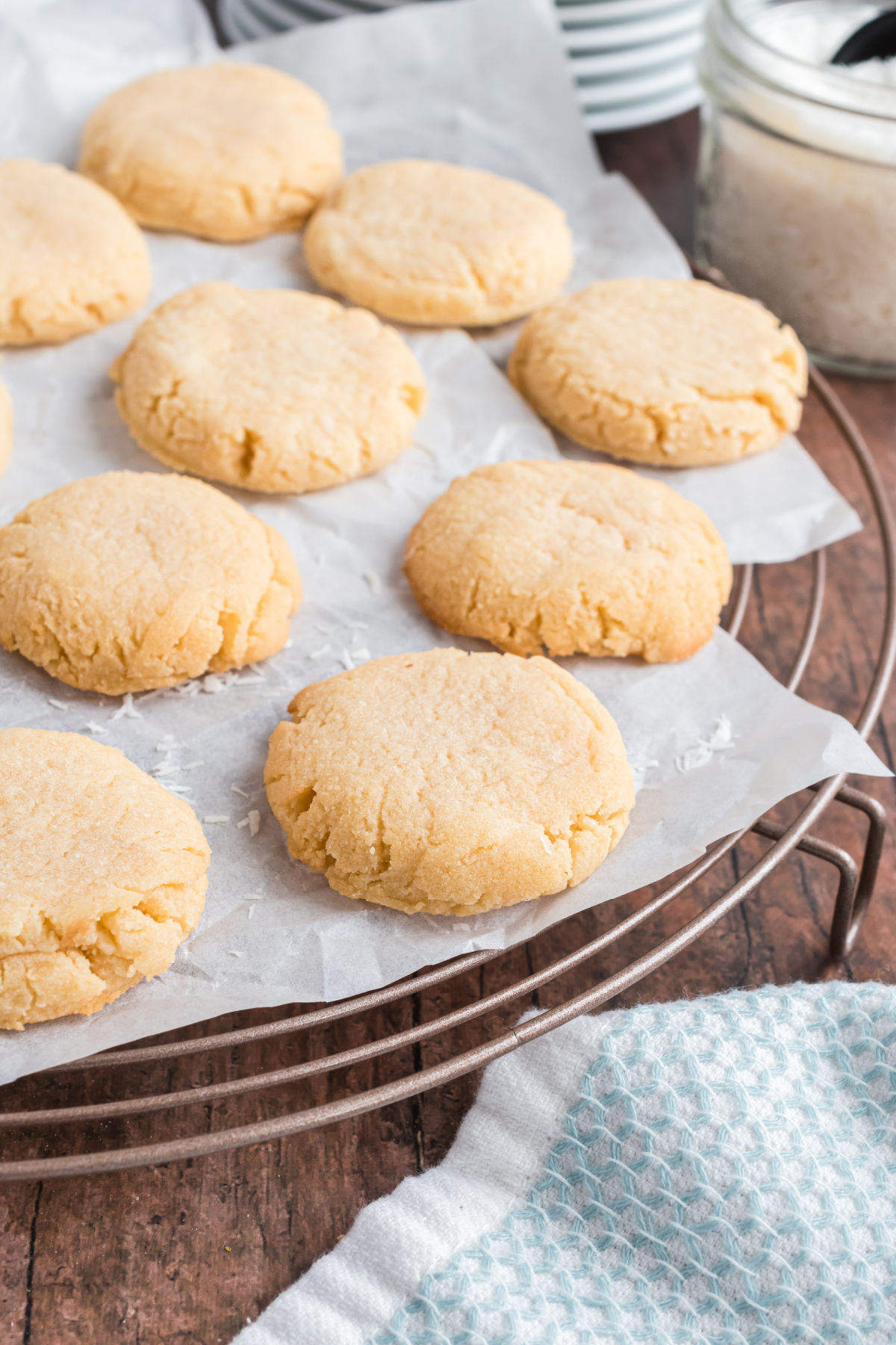 Coconut shortbread cookies on a parchment paper lined cooling rack.