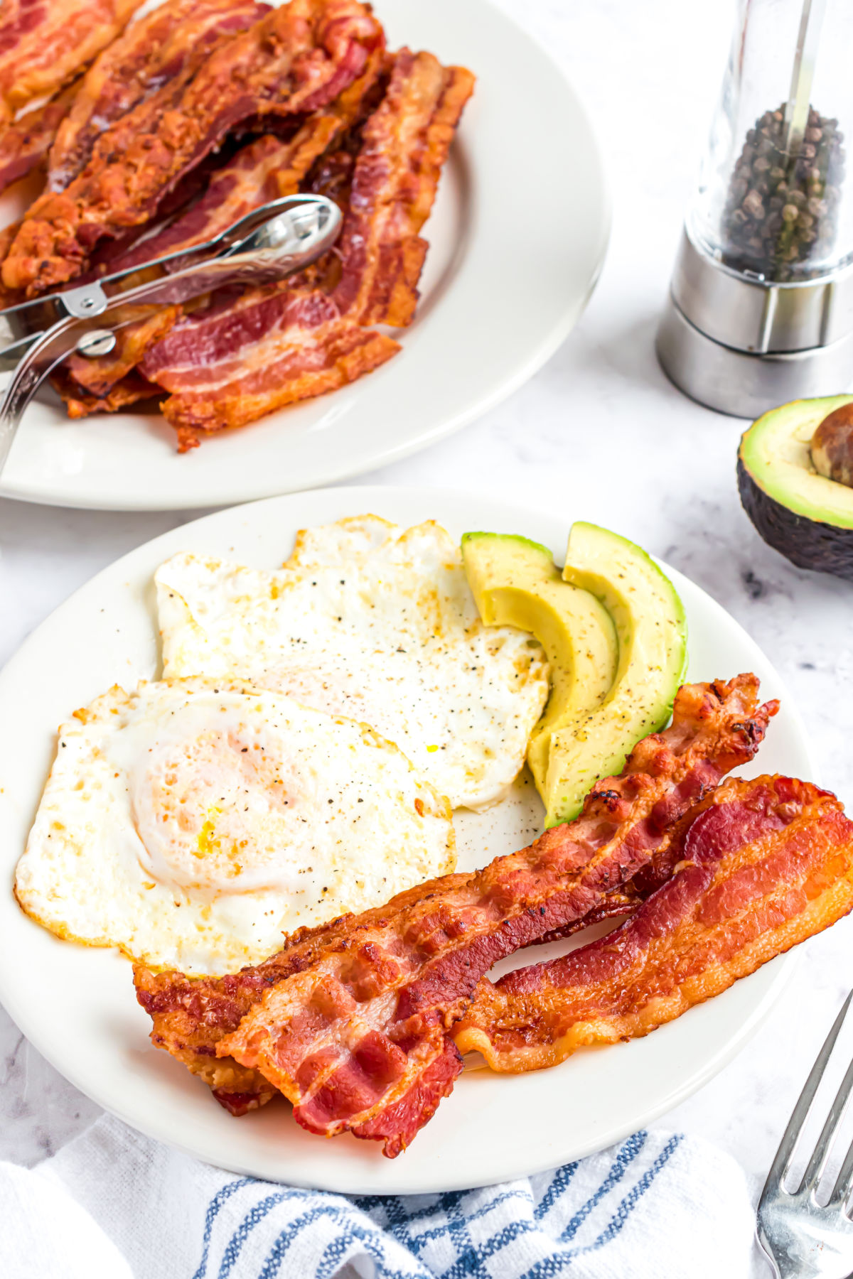 Cooked bacon with fried eggs on a plate.