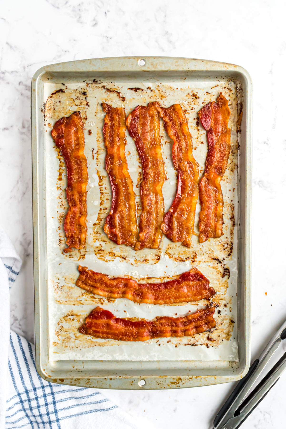 Bacon cooked on baking sheet with parchment paper.