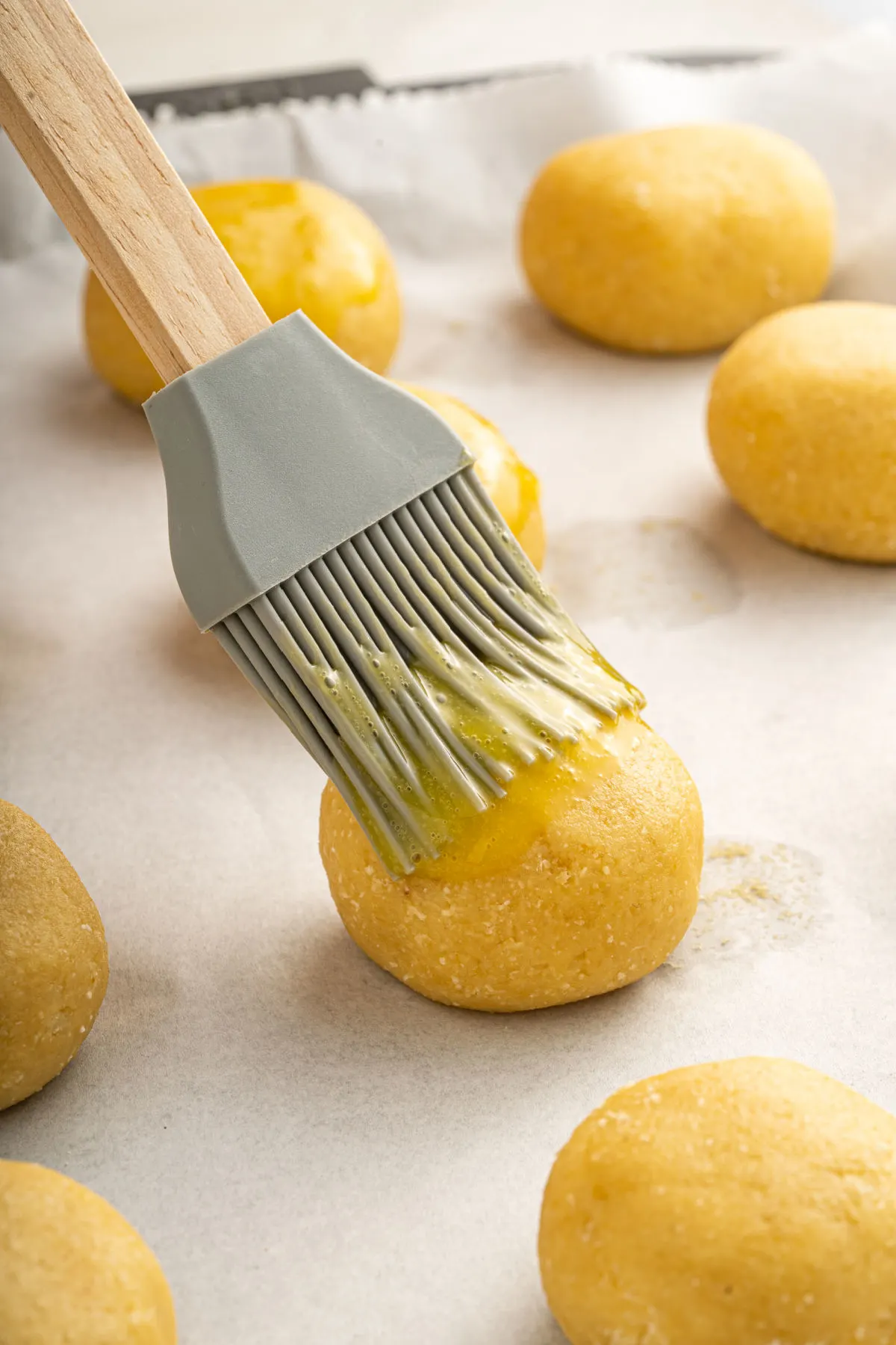 Unbaked buns being brushed with egg yolk.