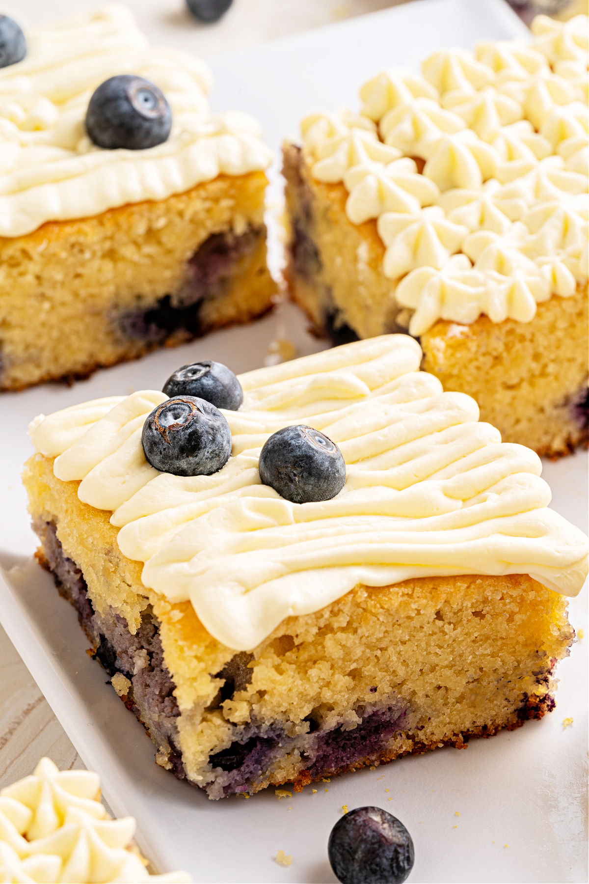Blueberry lemon cake sliced into squares on a white plate.