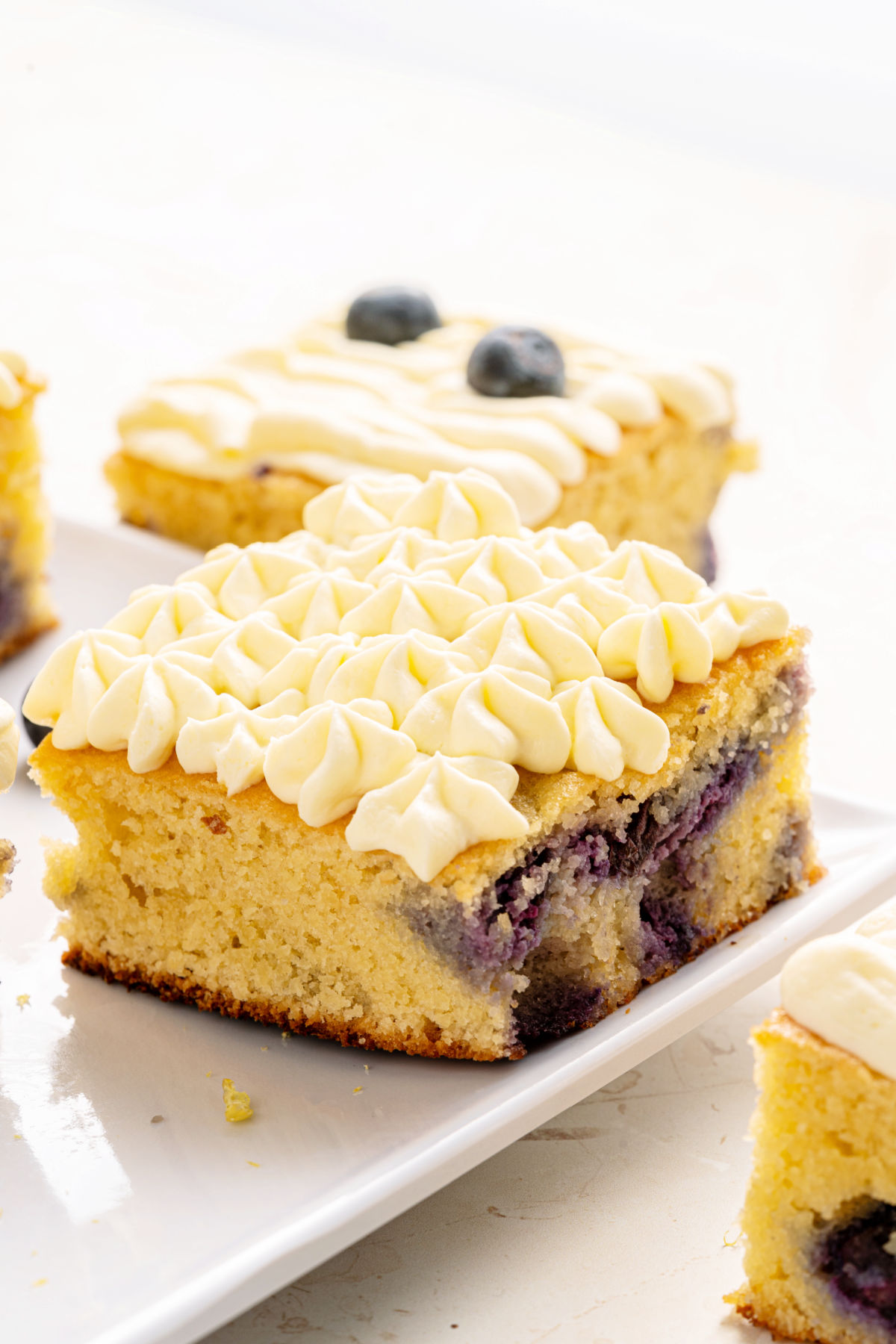 Blueberry cake with frosting on a white plate.